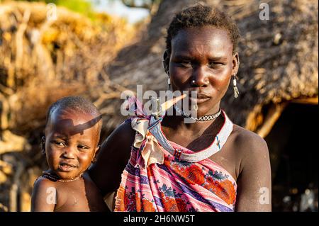 Donna della tribù Toposa con il suo bambino che fuma una pipa, Equatoria orientale, Sudan del Sud Foto Stock