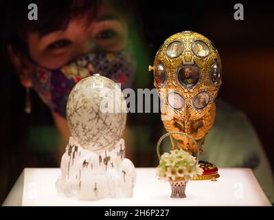 Un dipendente del museo guarda una vetrina contenente l'uovo d'inverno (primo piano) e l'uovo del tercentenario Romanov (sfondo) durante una telefonata per la prossima mostra del Victoria and Albert Museum 'Faberge a Londra: Romance to Revolution'. Data foto: Mercoledì 17 novembre 2021. Foto Stock