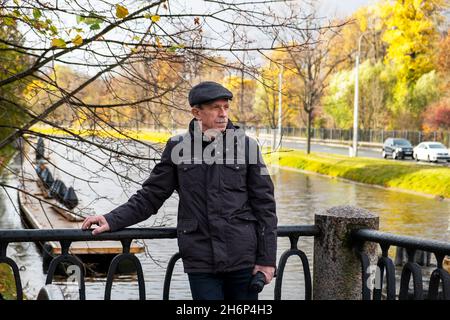 Anziano pensionato si trova in una bella giornata d'autunno nel parco cittadino Foto Stock