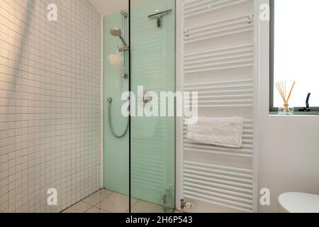Clare, Inghilterra - 9 marzo 2020: Bagno residenziale con doccia in parte piastrellata e vetrata in bianco e verde Foto Stock