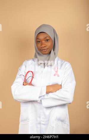 Assistenza sanitaria per le donne musulmane. Ritratto di una dottore afro-americano che indossa una bandana e cappotto bianco che posa con le braccia incrociate. pi. Verticale Foto Stock