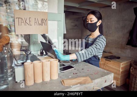 Barista in maschera protettiva che lavora in caffetteria Foto Stock