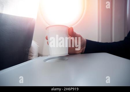 Il passeggero maschio dell'aeroplano beve acqua prima del decollo. Foto Stock