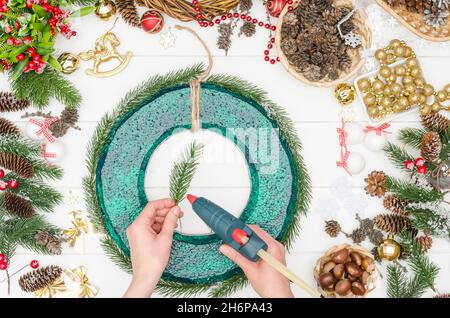 Passo per passo facendo una grande corona di Natale, passo 3 - incollare i rami artificiali con colla a caldo Foto Stock