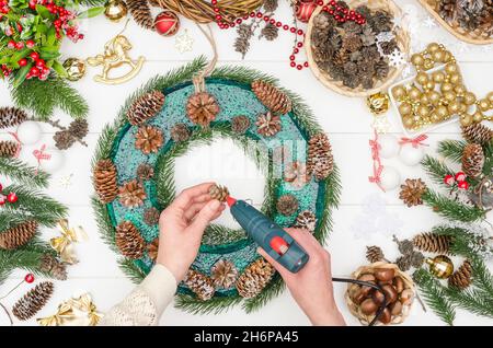 Facendo un grande wreath di Natale passo dopo passo, punto 8 - incollate i coni piccoli del larice con colla calda Foto Stock