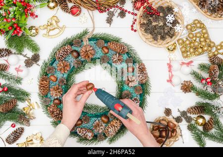 Facendo una grande corona di Natale passo dopo passo, passo 10 - incollare castagne naturali con colla a caldo Foto Stock