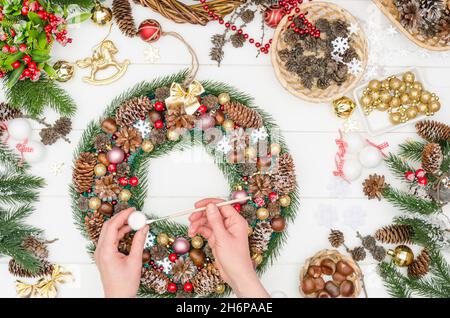 Facendo un grande wreath di Natale passo dopo passo, punto 20 - prenda la vernice acrilica bianca su un pennello Foto Stock