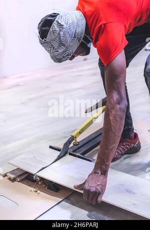 Johannesburg, Sudafrica - 15 novembre 2021: Uomo che taglia le tavole di pavimentazione con una taglierina. Foto Stock