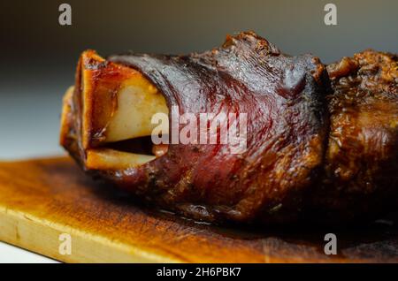 Gustoso e delizioso bacon arrosto con osso servito su un asse di legno, cibo taverna Foto Stock