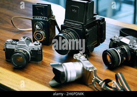 Izmir, Turchia - 9 luglio 2021: Immagine editoriale illustrativa di Lubitell 2, Mamiya RB67, Fujifilm xt4, Canon AE1 e Fujifilm XA2 fotocamera su un grou di legno Foto Stock