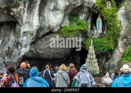 Pellegrini che pregano la statua della Vergine Maria nella grotta di nostra Signora di Lourdes, Francia Foto Stock