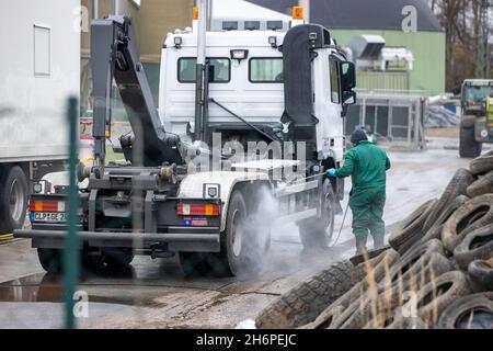 Vogelsang, Germania. 17 novembre 2021. Un dipendente pulisce un camion con un pulitore ad alta pressione nei locali della fattoria suinicola colpita dalla peste suina africana. È in corso la messa a punto dell'attrezzatura tecnica per l'uccisione degli oltre 4,000 suini. Il primo focolaio di peste suina africana nel Meclemburgo-Pomerania occidentale si è verificato presso l'impianto. Come reazione all'epidemia di ASF nel bestiame nel distretto di Rostock, tutti gli animali devono ora essere abbattuti e smaltiti. Credit: Jens Büttner/dpa-Zentralbild/dpa/Alamy Live News Foto Stock