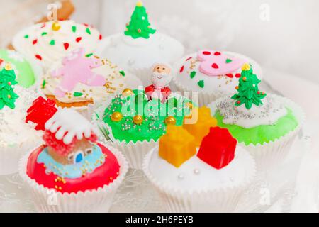Torte fatte in casa, cupcake, muffin decorati in stile natalizio. Mini cupcake da dessert natalizi di stagione in simboli decorativi tradizionali e Foto Stock