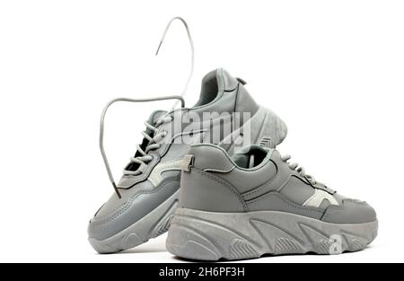 Sneaker beige da donna su sfondo bianco. Sneaker ragguaricante con lacci volanti. Foto Stock