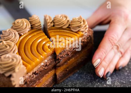 Affettare una deliziosa e splendida torta al caramello al cioccolato. Foto Stock