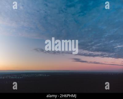 Vista aerea oscura su foresta scura al tramonto. Le pesanti nuvole blu che coprono la colorata scena del cielo serale Foto Stock