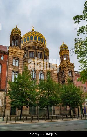 Bella vista della Nuova Sinagoga sulla via Oranienburger Straße a Berlino, in Germania, in una giornata nuvolosa. La cupola principale della sinagoga, con le sue costolette dorate,... Foto Stock