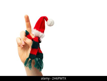 Vista ravvicinata della mano della persona isolata mostra il gesto di pace, indossando un cappello di Natale e una sciarpa a maglia rossa e verde. Molto spazio per la copia. Foto Stock
