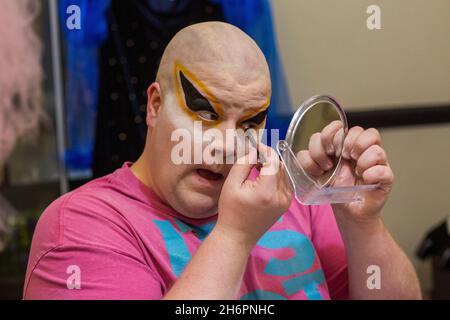 Maschio drag queen applicare drammatico make up in preparazione per una performance . Foto Stock