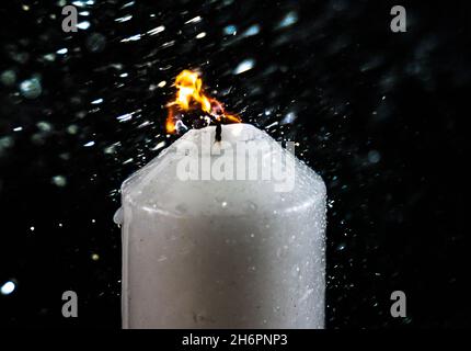 Processo di una candela illuminata che ottiene soffiata fuori dall'acqua su uno sfondo nero Foto Stock