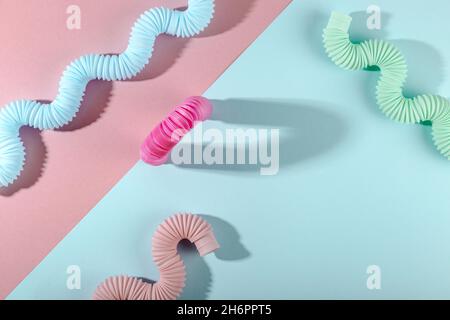 Giocattolo curvo rosa blu menta antistress pop tube con ombra su sfondo rosa. Giocattolo per bambini luminoso. Foto Stock