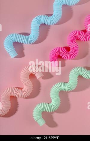 Giocattolo curvo rosa blu menta antistress pop tube con ombra su sfondo rosa. Giocattolo per bambini luminoso Foto Stock