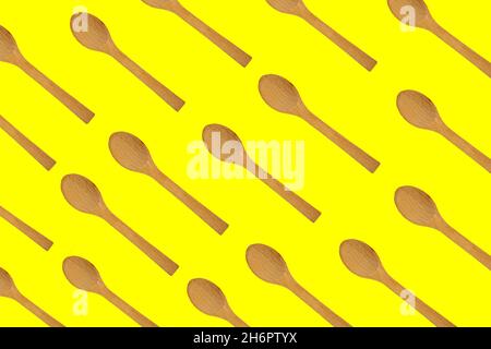 Cucchiai di legno, vista dall'alto di cucchiai di legno isolati su sfondo giallo. Sfondo del motivo degli utensili da cucina. Foto Stock