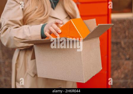 Pacco di raccolta. Donna mani con scatole a macchina automatica esterna pacchi. Concetto di recapito postale e servizio postale. Foto Stock