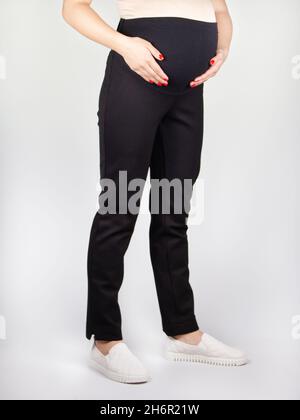 Abbigliamento per pantaloni incinta, nero con vita alta isolato su sfondo bianco, concetto di gravidanza Foto Stock
