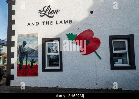 Ricordo papaveri e pittura su un pub parete, il Leone e l'Agnello nel villaggio di Gosforth, Cumbria, Regno Unito, per segnare il giorno armistizio, 2021 novembre Foto Stock