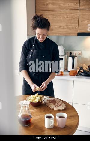 bella donna mediorientale che prepara le mele per cucinare all'accogliente cucina stillish Foto Stock