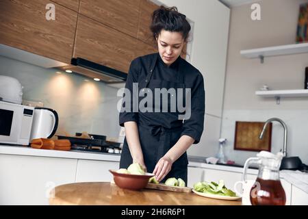 bella donna mediorientale che prepara le mele per cucinare all'accogliente cucina stillish Foto Stock