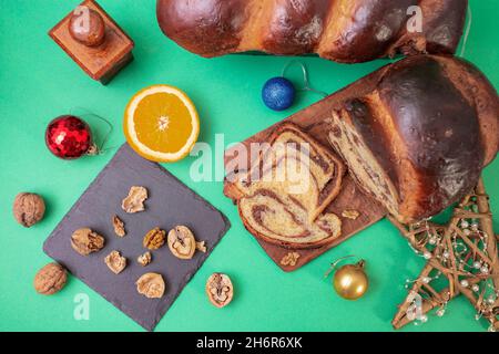 Cozonac (pane dolce) con noci e decorazioni natalizie su sfondo verde Foto Stock