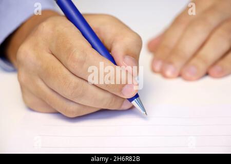 Mano maschio con penna, uomo in camicia blu firma la carta. Concetto di impiegato, uomo d'affari, conclusione del contratto Foto Stock