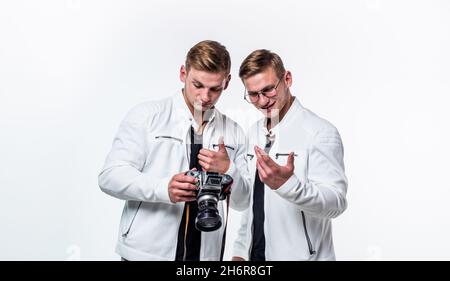 gli uomini gemelli dei fratelli osservano allo stesso modo usano la macchina fotografica vintage, fotografando Foto Stock