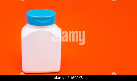 vaso per pillola bianco senza marchio. flacone multivitaminico su sfondo arancione. spazio copia. supplemento cibo. Foto Stock