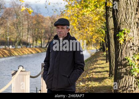 Anziano pensionato si trova in una bella giornata d'autunno nel parco cittadino Foto Stock