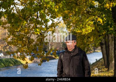 Anziano pensionato si trova in una bella giornata d'autunno nel parco cittadino Foto Stock