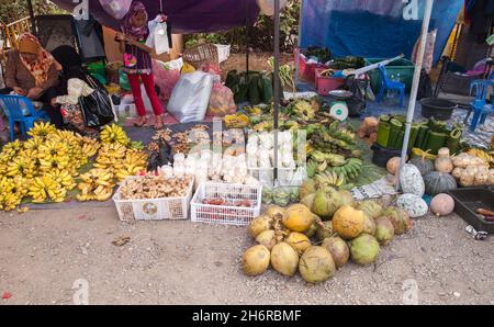Kota Kinabalu, Malesia - 23 marzo 2019: La frutta locale si è posata sul terreno al mercato di Kota Kinabalu, la bambina si trova vicino agli adulti Foto Stock