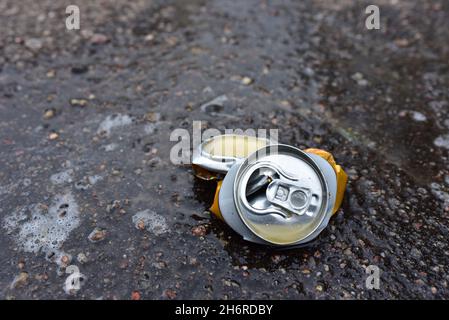 Sminuzzata una lattina di birra su asfalto con alcol versato. Gettato la lattina di bevanda carbonata rotta ad una strada. Problema sociale, criminalità. Inquinamento ambientale, Foto Stock