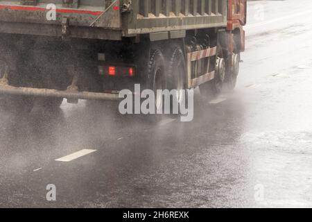 autocarro pesante in movimento su strada bagnata con spruzzi durante il giorno Foto Stock