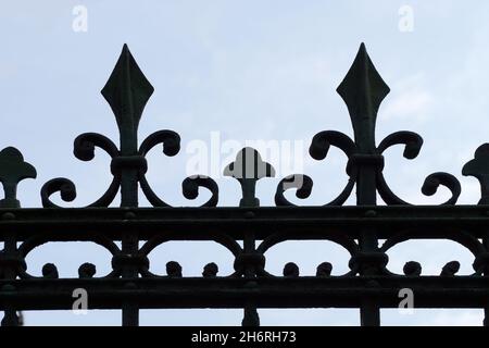 frammento di recinto vintage forgiato con cime affilate contro il cielo. Foto Stock