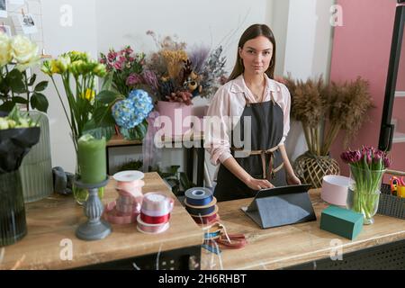 Fiorista professionista giovane donna sta facendo i mazzi al negozio di fiori Foto Stock