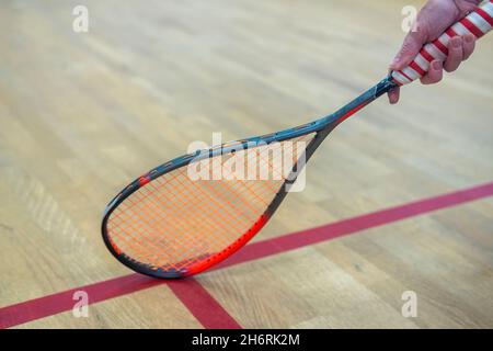 donna mano che tiene racket squash sulla linea sul pavimento. Foto Stock