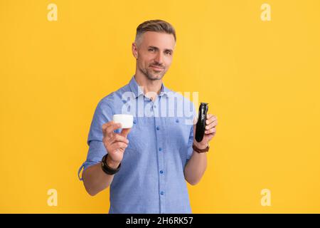 barbiere. dopo la rasatura. l'uomo tiene il rasoio elettrico e la crema. il ragazzo grizzled presenta il rasoio elettrico Foto Stock