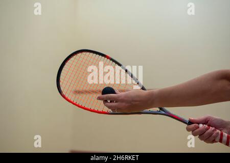mano femmina che tiene una racchetta da squash e colpisce la palla. Foto Stock