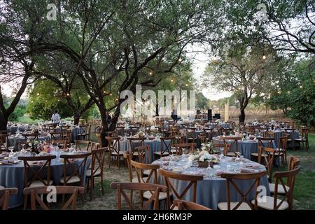 Tavoli e sedie rotondi preparati per una festa all'aperto in un parco Foto Stock