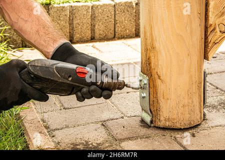 Gli operatori che indossano i guanti devono utilizzare un cacciavite elettrico per serrare la vite. Foto Stock
