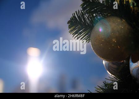 Primo piano delle decorazioni natalizie con la luce che si riflette sugli edifici sul retro con cielo blu chiaro Foto Stock