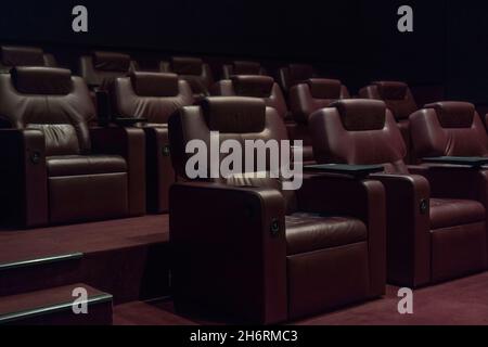 file di poltrone in pelle marrone in una sala cinema vuota in un cinema durante la quarantena del coronavirus. Foto Stock